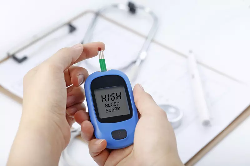 hand with blood glucose meter showing high blood sugar