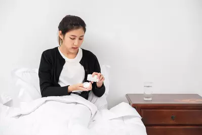 woman taking medicine in bed